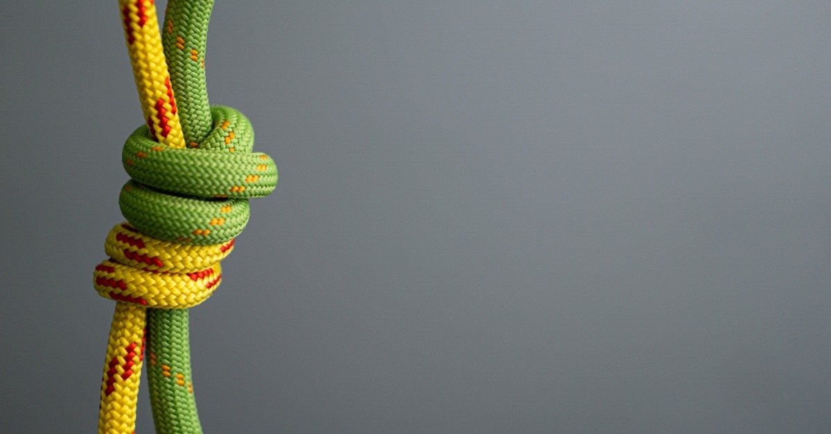 A close-up of a yellow climbing rope and a green climbing rope connected with a double fisherman's knot.